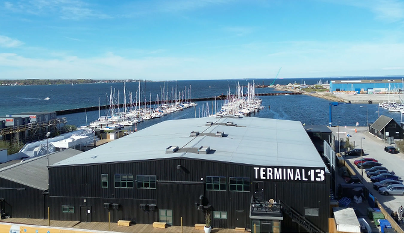 Terminal 13 set fra luften med parkering langs bygningen og havnen bagved
